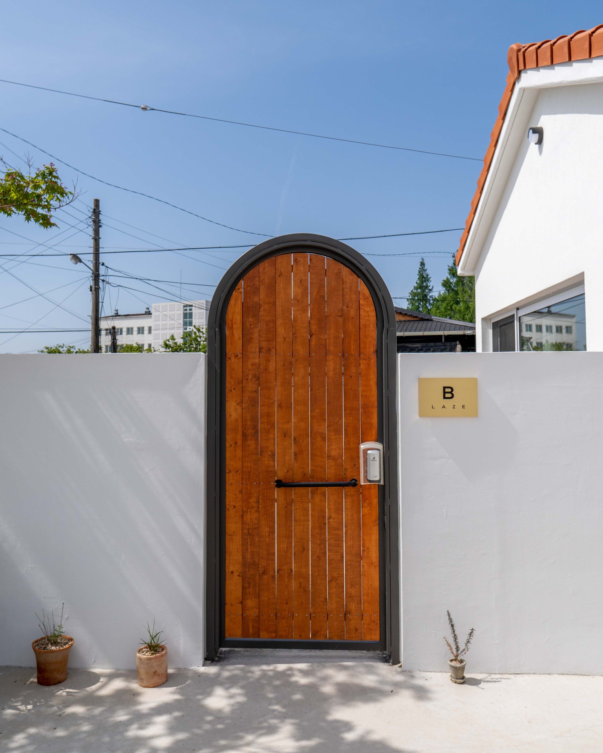 LAZE B entrance with arched oak door and potted plants